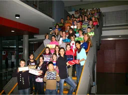 Kinder stehen mit bunt bepackten Schuhkartons auf der Treppe im Schulgebäude.