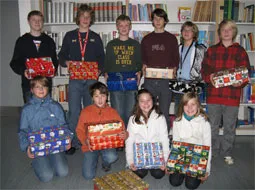 Jugendliche halten in der Bücherei bunt verpackte Weihnachtspäckchen in die Kamera.