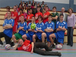 Die Mannschaften stehen in Sporttrikots mit Bällen in der Sporthalle.