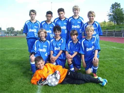 Die Fußballmannschaft in blauen Trikots stellt sich auf dem Sportplatz auf.
