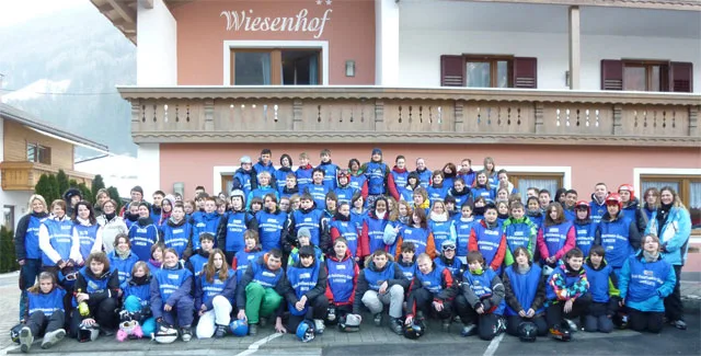 Die Skigruppe in blauen Jacken steht vor dem Gästehaus im Ahrntal.
