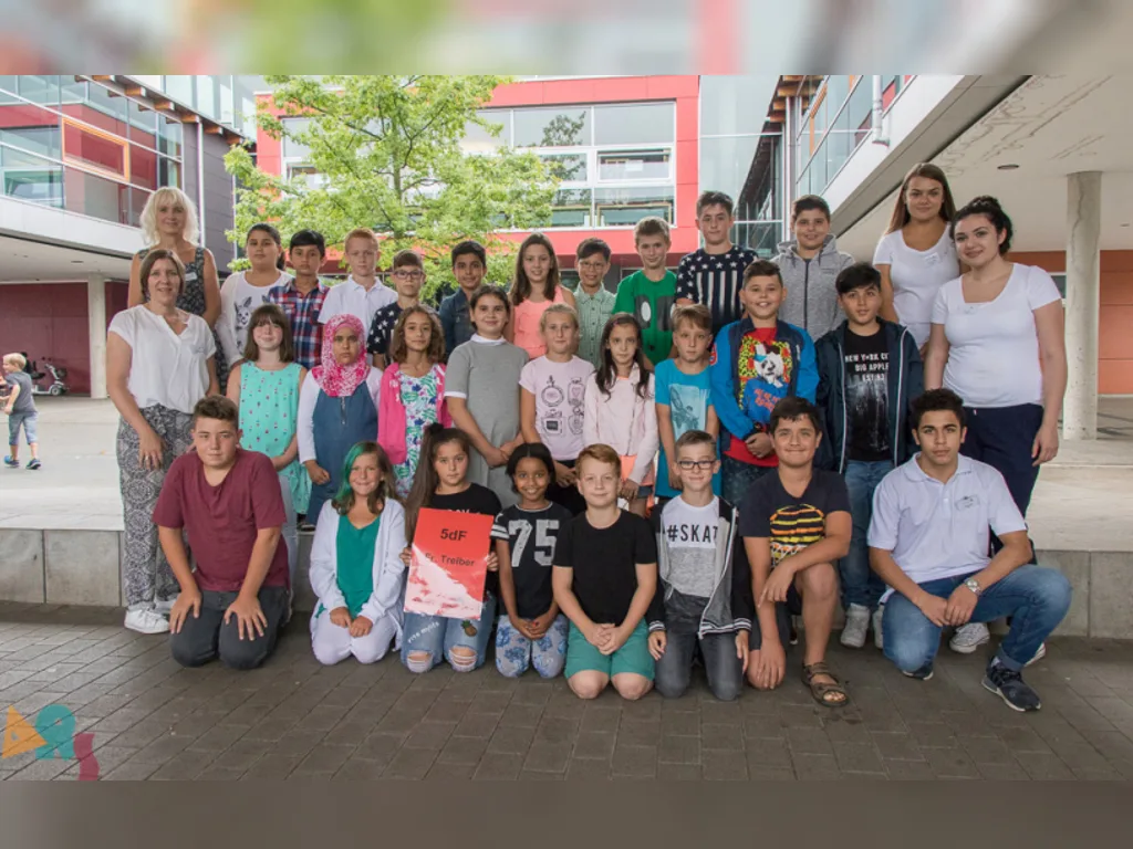 Klassenfoto einer neuen fünften Klasse mit zwei Lehrkräften im Innenhof.