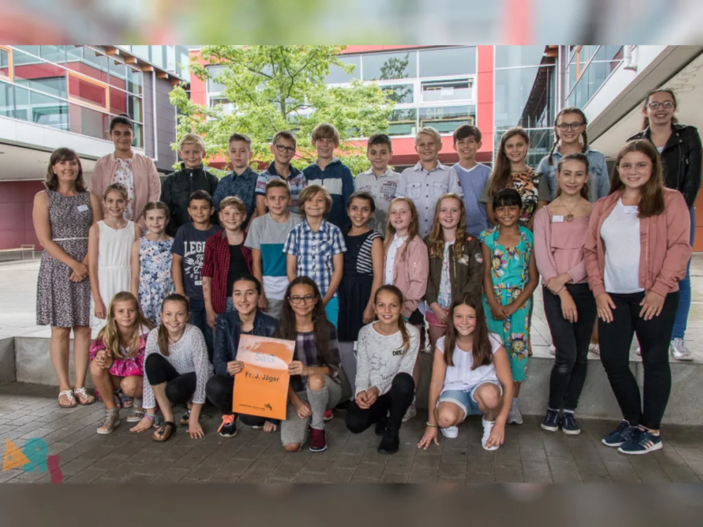 Klassenfoto einer neuen fünften Klasse, ein Kind hält das orangefarbene Klassenschild.