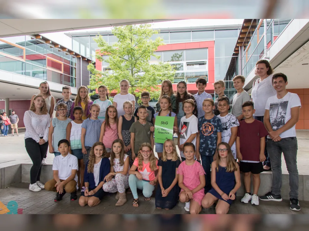 Klassenfoto einer neuen fünften Klasse auf den Stufen im Innenhof, einige halten Schilder.