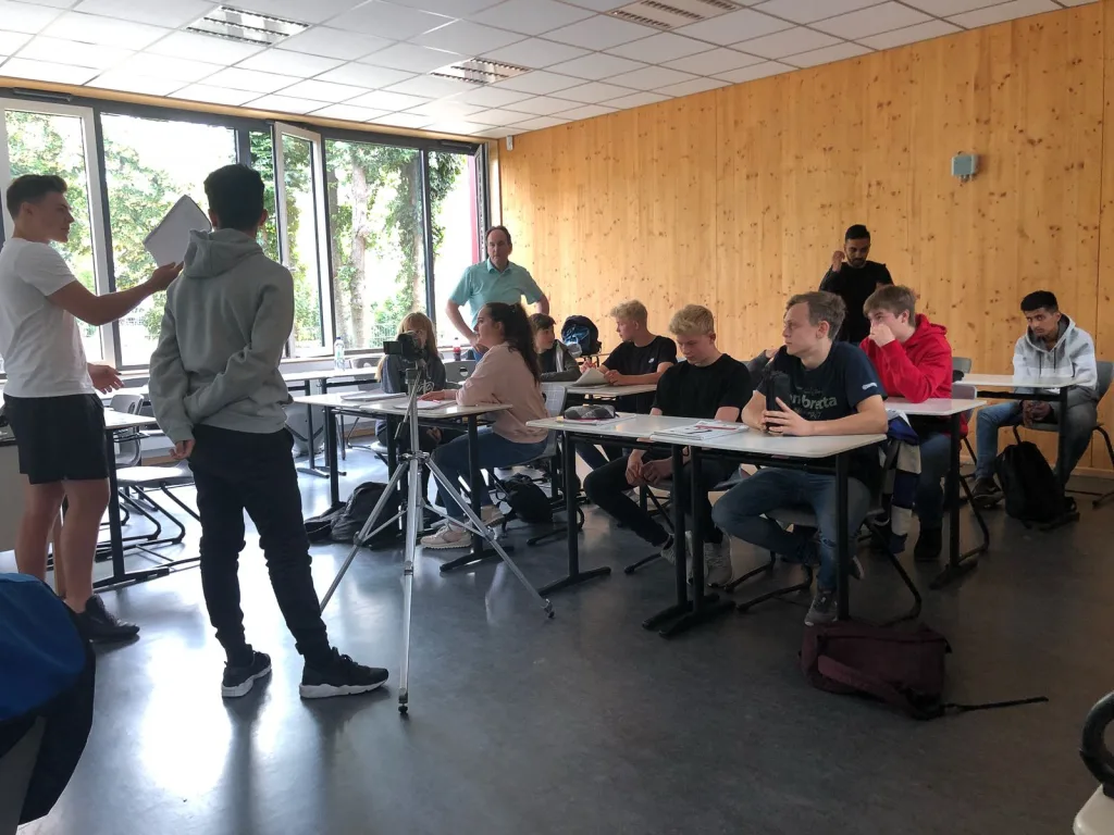 Jugendliche tragen vor einer Klasse etwas vor.