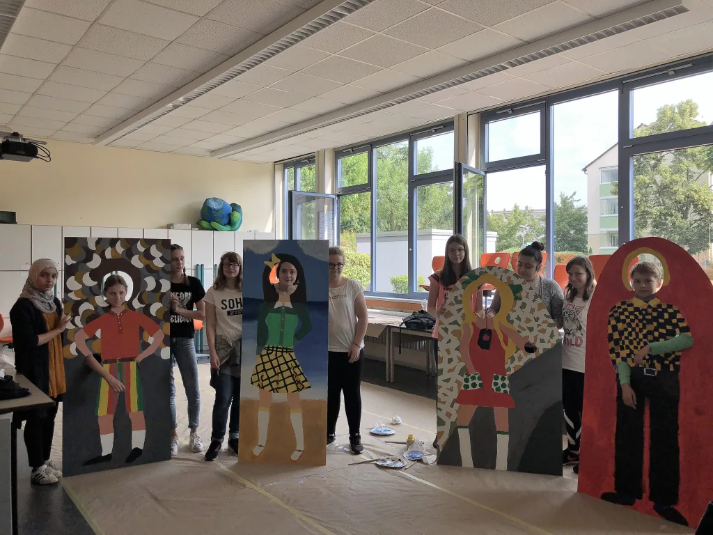 Gruppe präsentiert selbst gebaute Figuren im Klassenraum.