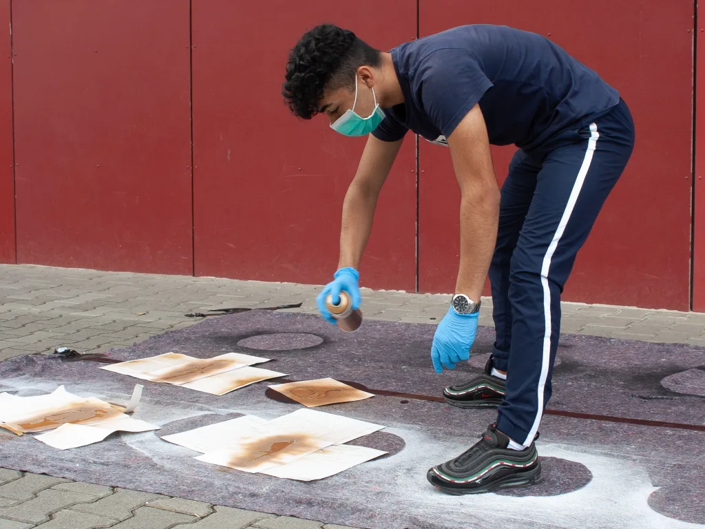 Jugendlicher arbeitet an einem Druckversuch auf dem Boden.