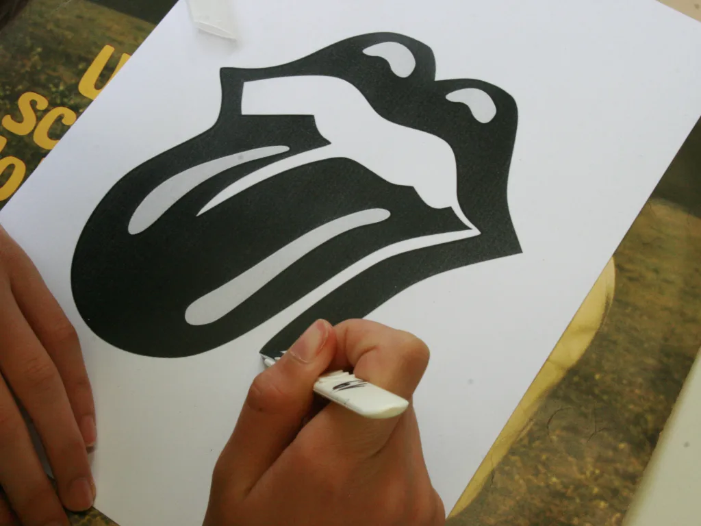 Hand zeichnet ein Bandlogo auf ein Blatt.