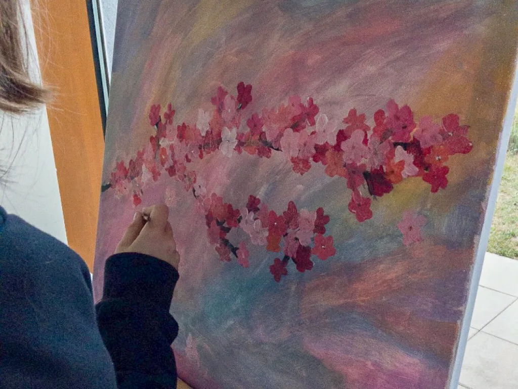 Gemälde mit Kirschblüten auf einer Staffelei.