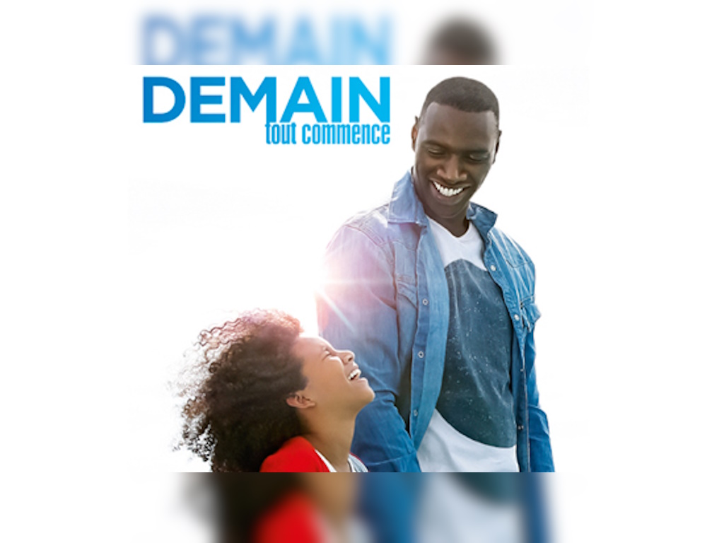 Filmplakat zu „Demain tout commence“: ein lachender Mann blickt zu einem fröhlichen Kind hinab; oben der blaue Schriftzug „DEMAIN tout commence“.