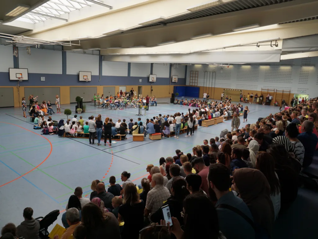 Weite Aufnahme der voll besetzten Sporthalle.