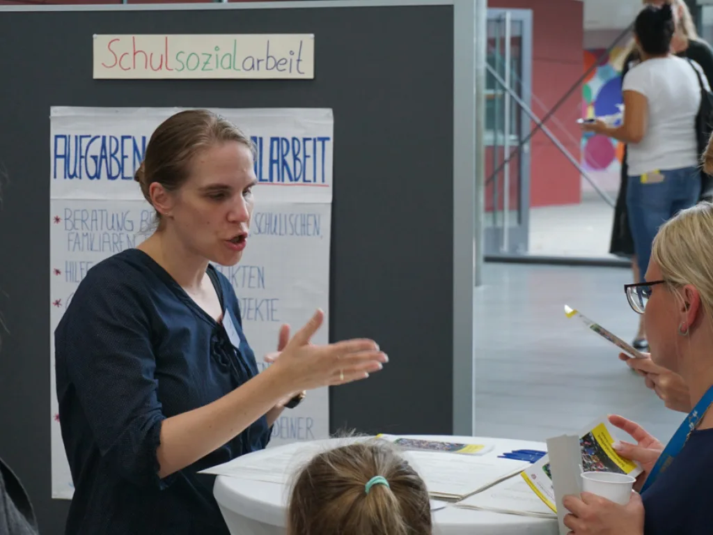 Person erklärt an einer Stellwand die Schulsozialarbeit.