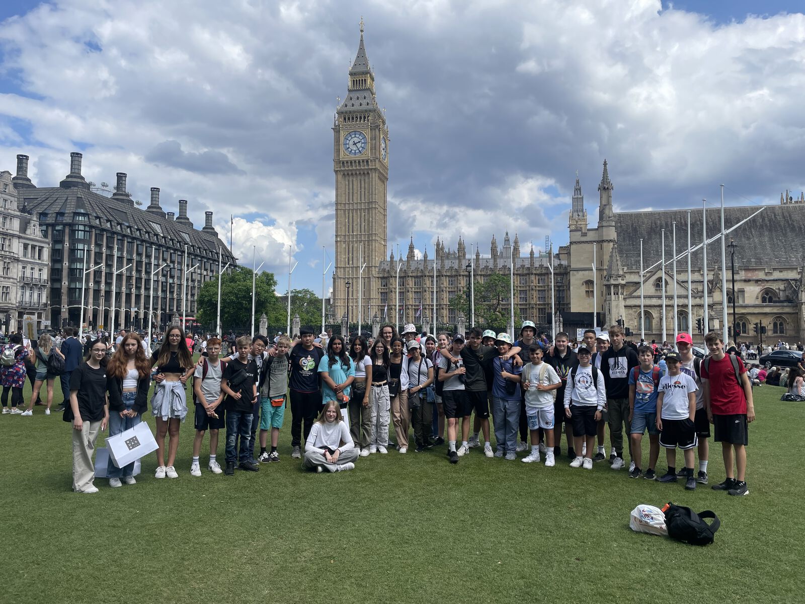 Eine große Schülergruppe posiert auf einer Rasenfläche vor dem Big Ben und den Houses of Parliament in London.
