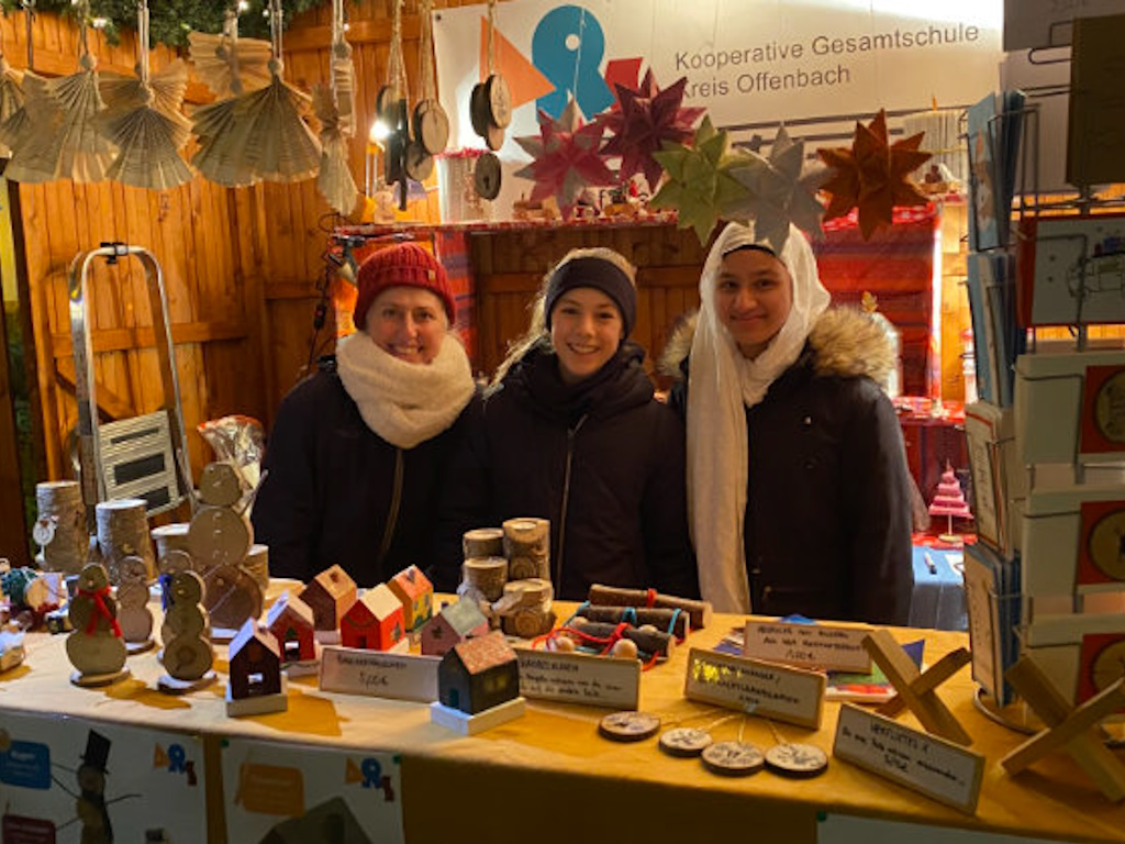 Frau Dahmer (links) gemeinsam mit zwei engagierten Jugendlichen während ihrer Schicht in der ARS-Hütte auf dem Weihnachtsmarkt in Langen.