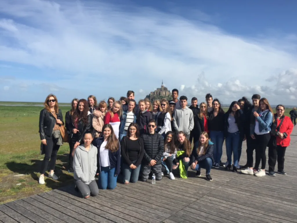 Die Reisegruppe steht auf einer Aussichtsplattform, im Hintergrund der Mont-Saint-Michel.