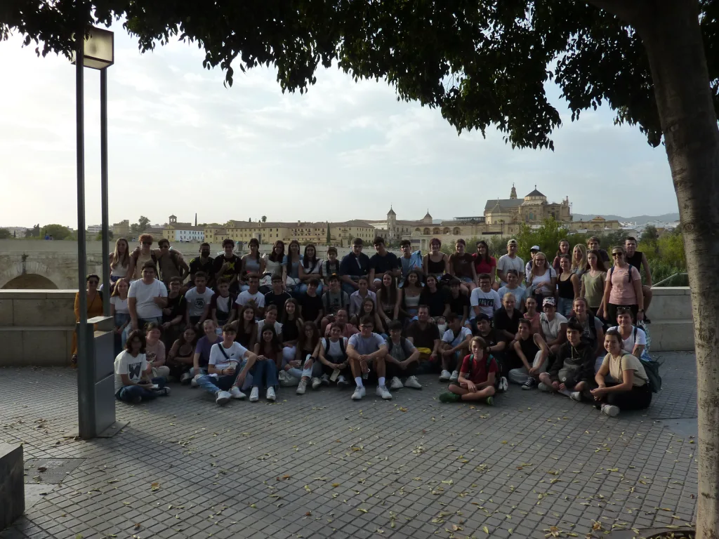 Eine große Gruppe sitzt auf einem Platz, im Hintergrund die Mezquita von Córdoba.