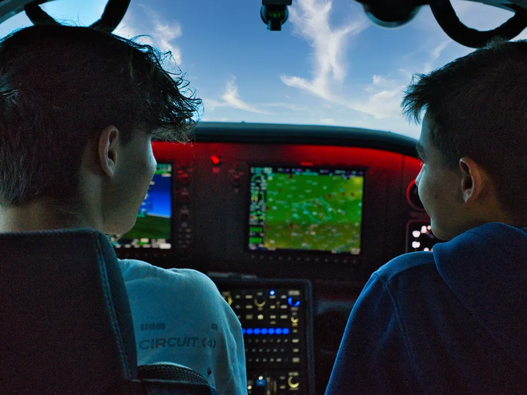Zwei Jugendliche im Cockpit schauen durch die Frontscheibe nach draußen.