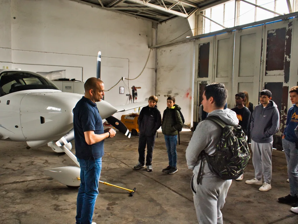 Ein Fachmann erklärt der Gruppe im Hangar ein Flugzeug.
