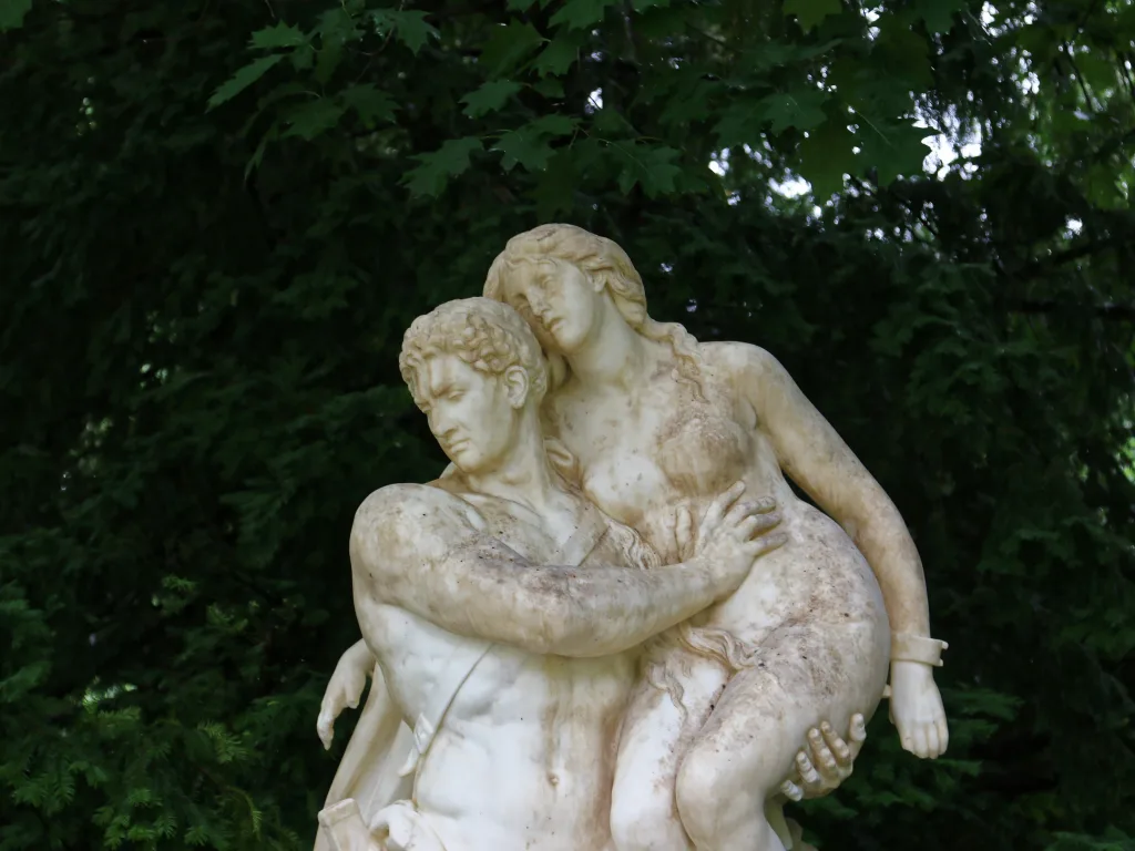 Steinerne Figurengruppe im Park zwischen Bäumen.
