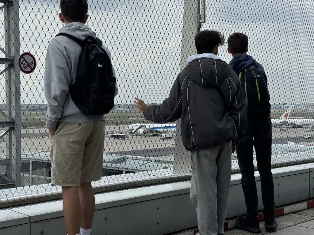 Drei Jugendliche beobachten die Flugzeuge am Flughafen.