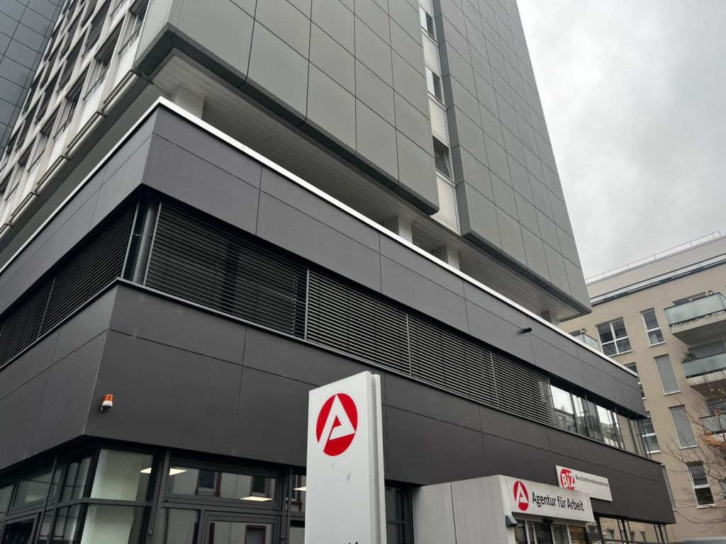 Das Bürogebäude der Agentur für Arbeit in Offenbach mit dem roten „A“-Logo am Eingang; im oberen Bereich ein Schild „BiZ Berufsinformationszentrum“.