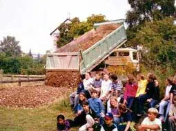 Ein Lastwagen kippt Sand für das Heidebiotop ab, davor sitzen die beteiligten Kinder.