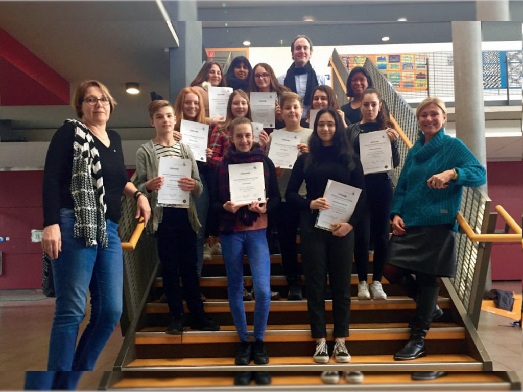 Schüler und Schülerinnen halten Urkunden in die Kamera